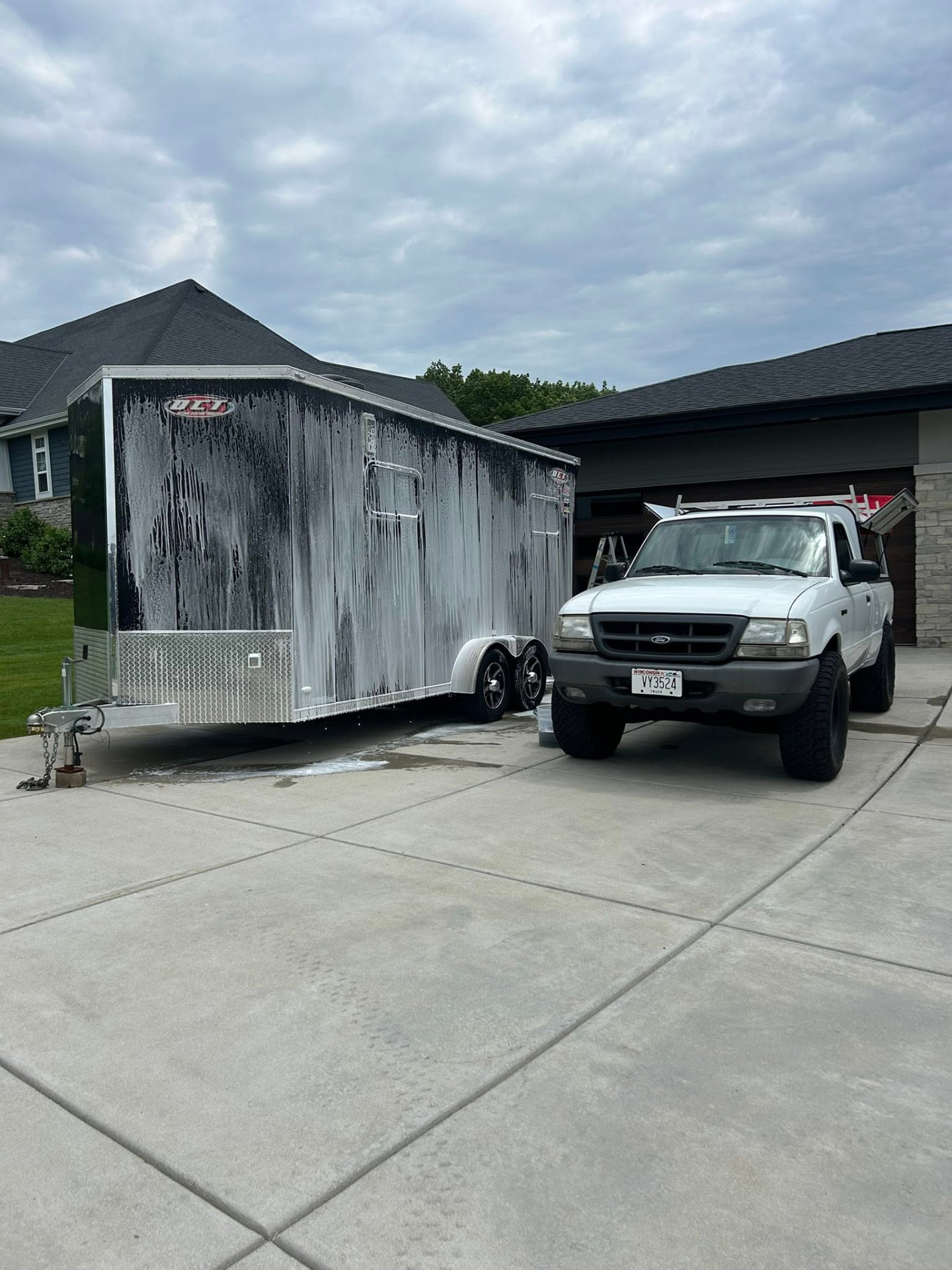 White Ford Ranger pickup and a race trailer covered in snow foam during a wash