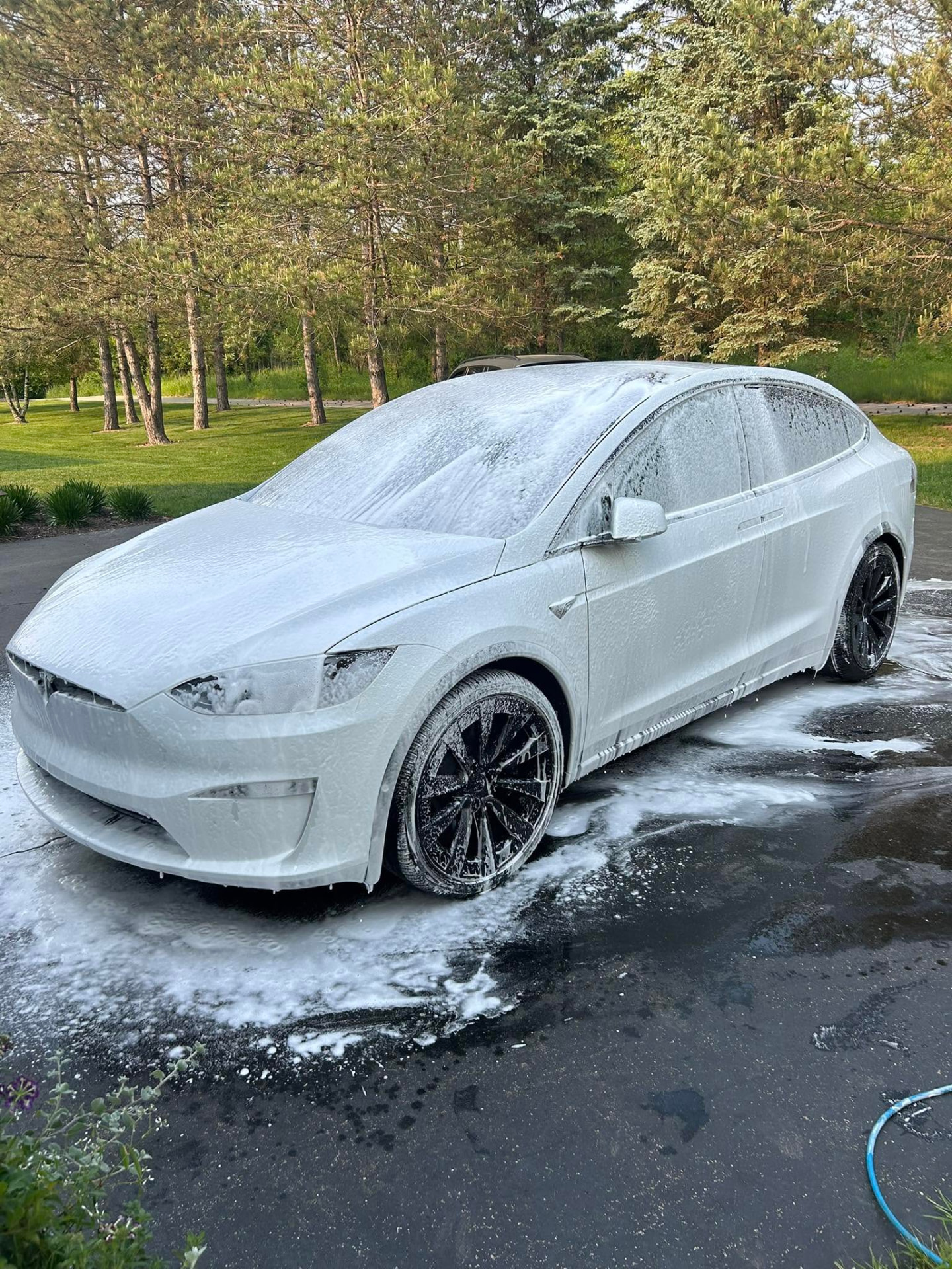 White Tesla Model X covered in snow foam during a wash