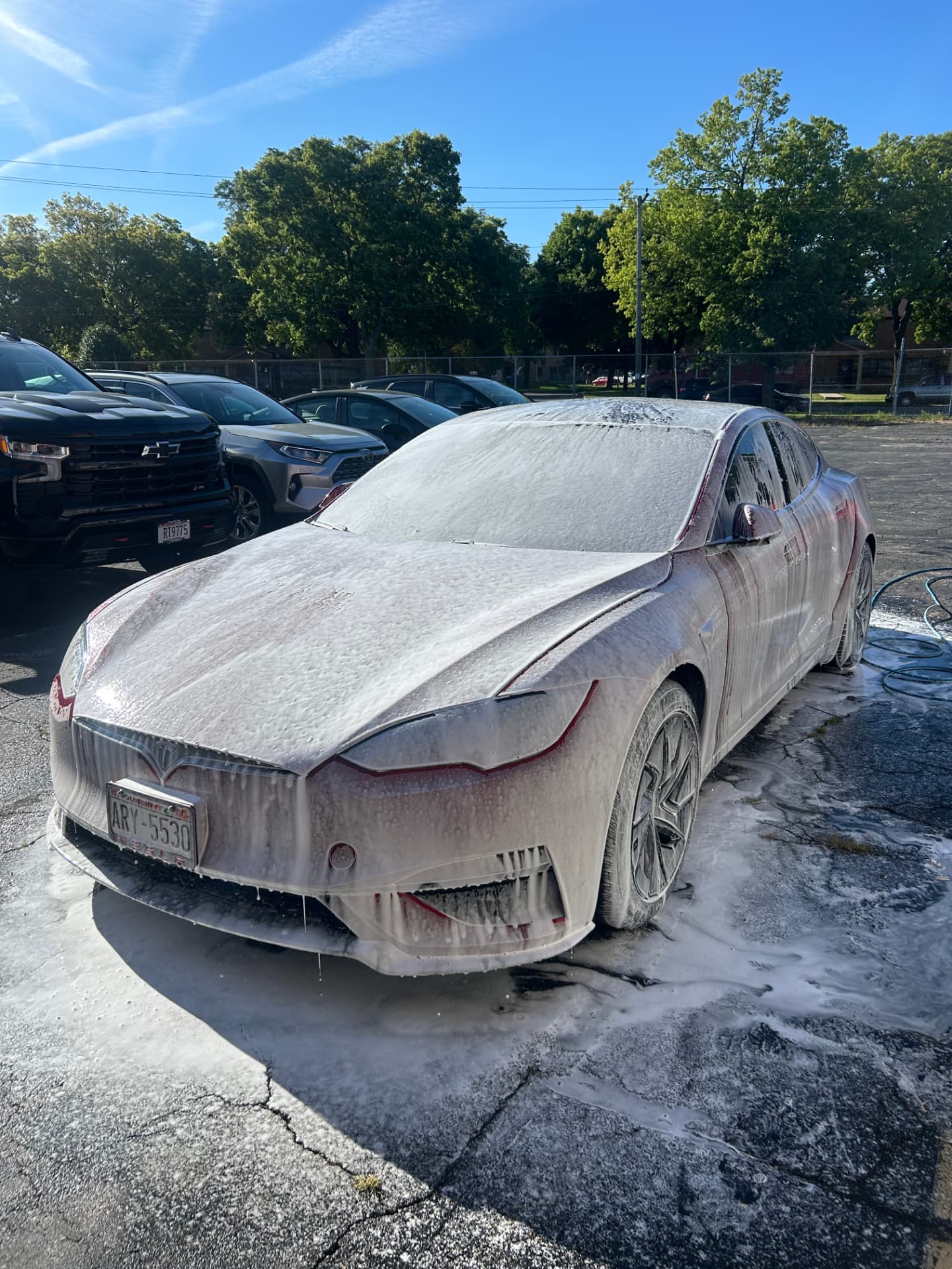 Red Tesla Model S covered in snow foam during a wash